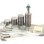 Stack of coins and Indian currency on white background