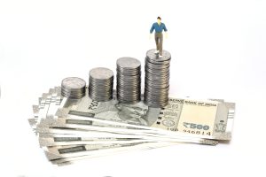 Stack of coins and Indian currency on white background